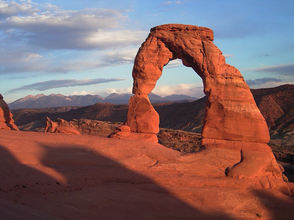 Delicate Arch standing on slickrock against a deep blue sky