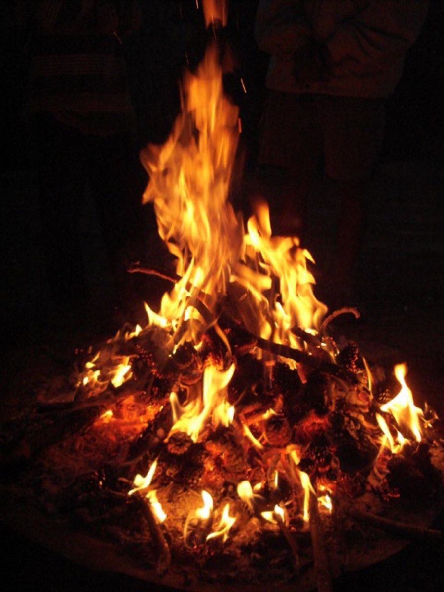 A small campfire burning in a stone ring at a campsite