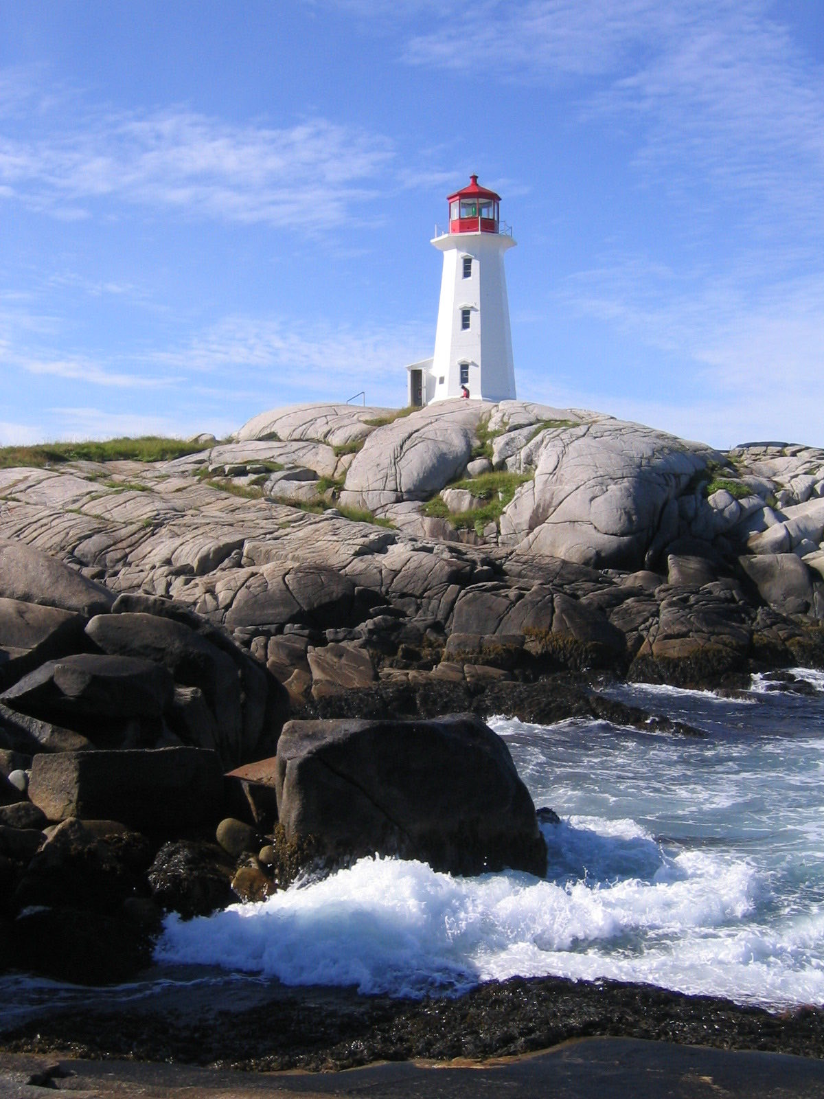 The white lighthouse at Peggy's Cove standing over wave-washed granite