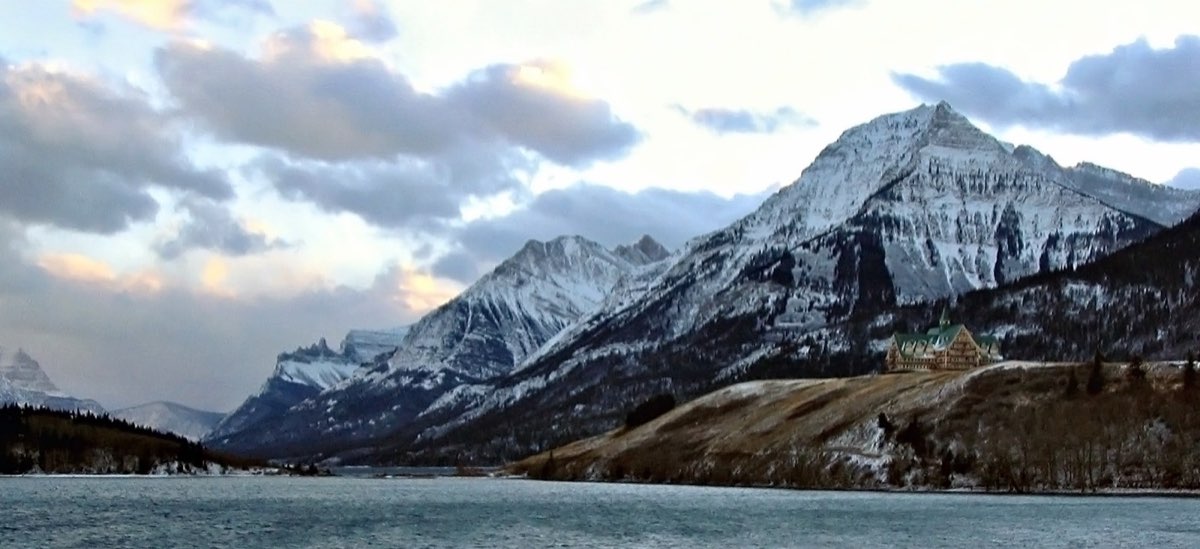 Mountains rising directly from flat prairie beside a lake at Waterton