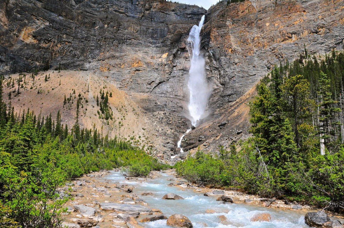 Emerald green lake water beneath steep forested mountains in Yoho National Park